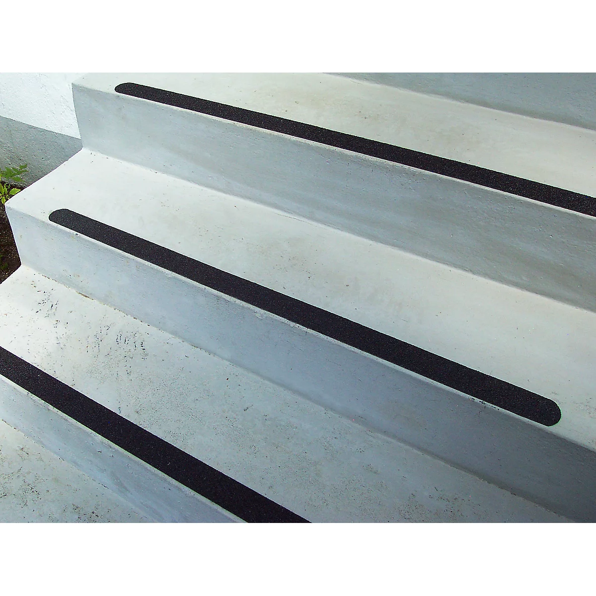 Concrete steps with black anti-slip strips. The angle of view is slightly from below.