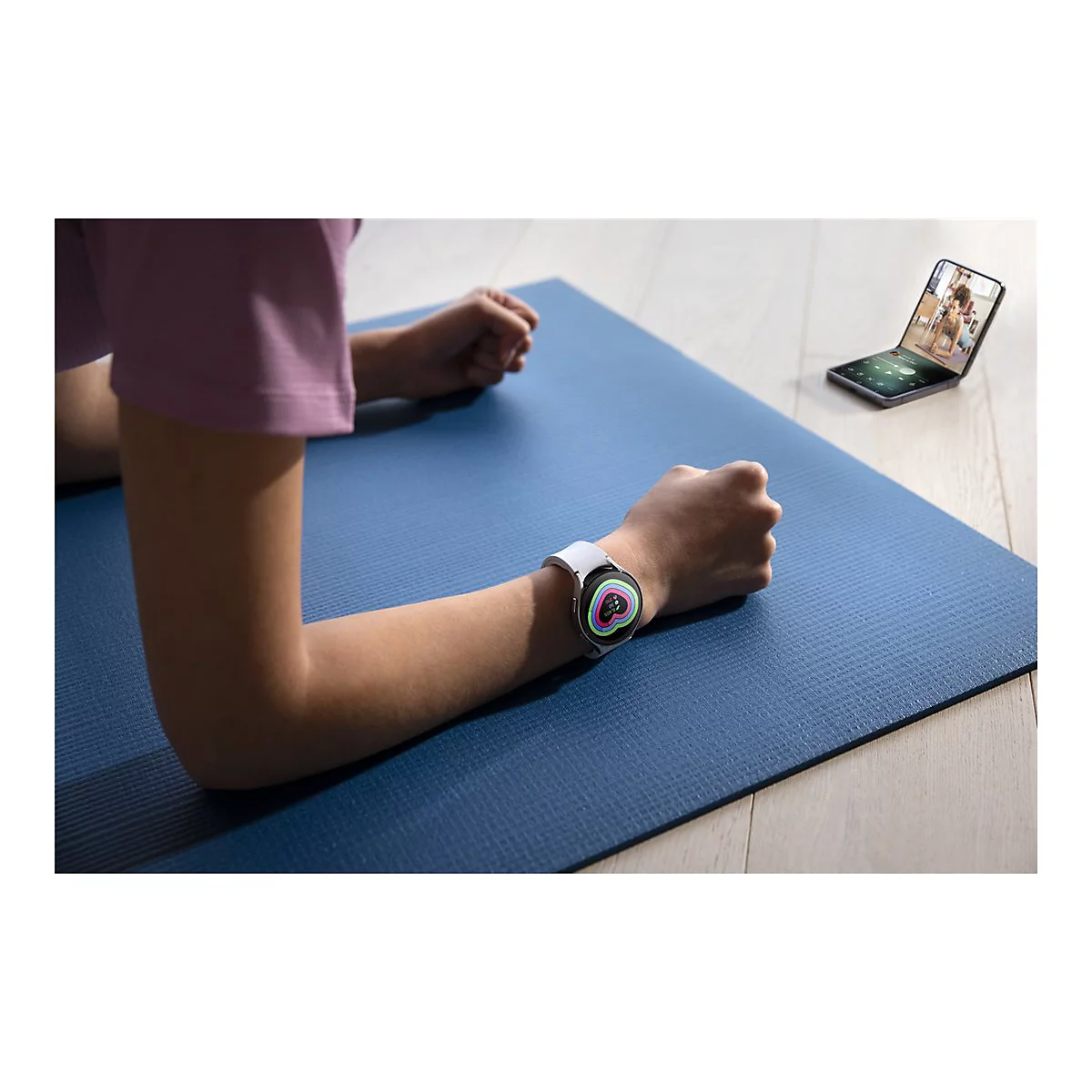 Person in Plank-Position auf blauer Matte mit Smartwatch und Handy, das Workout anzeigt.