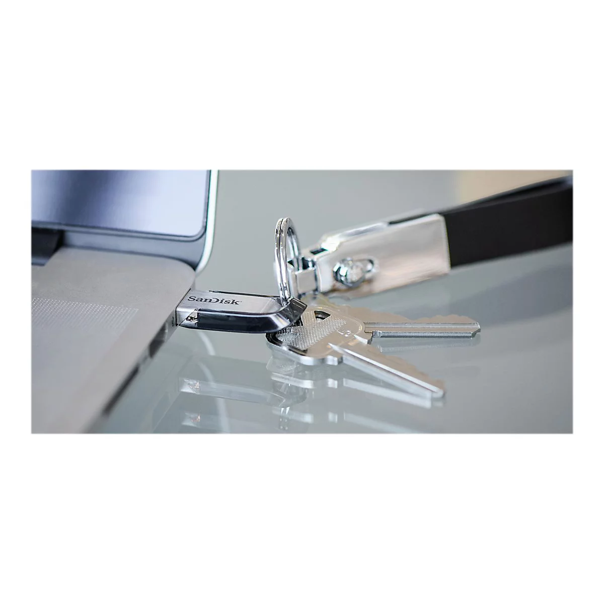 ClÃ© USB avec porte-clÃ©s insÃ©rÃ© dans un ordinateur portable, avec deux clÃ©s Ã  cÃ´tÃ©. Surface grise.