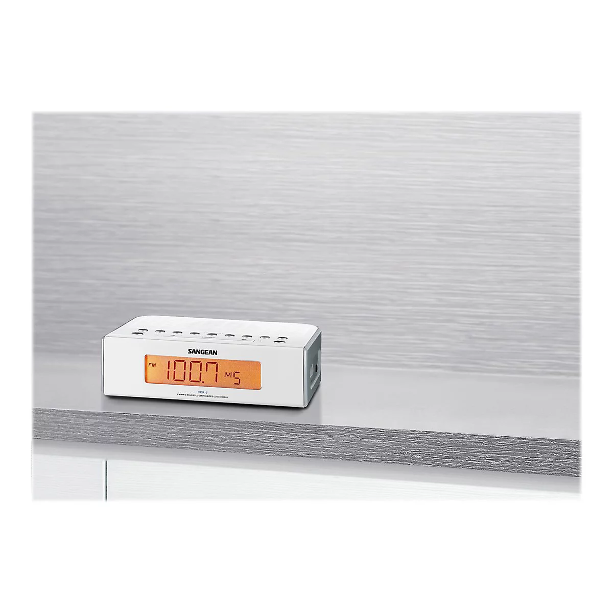 WeiÃŸes Digitalradio mit orangefarbener Anzeige, auf einem Regal platziert. Der Bildschirm zeigt die Frequenz an. Oben befinden sich KnÃ¶pfe.
