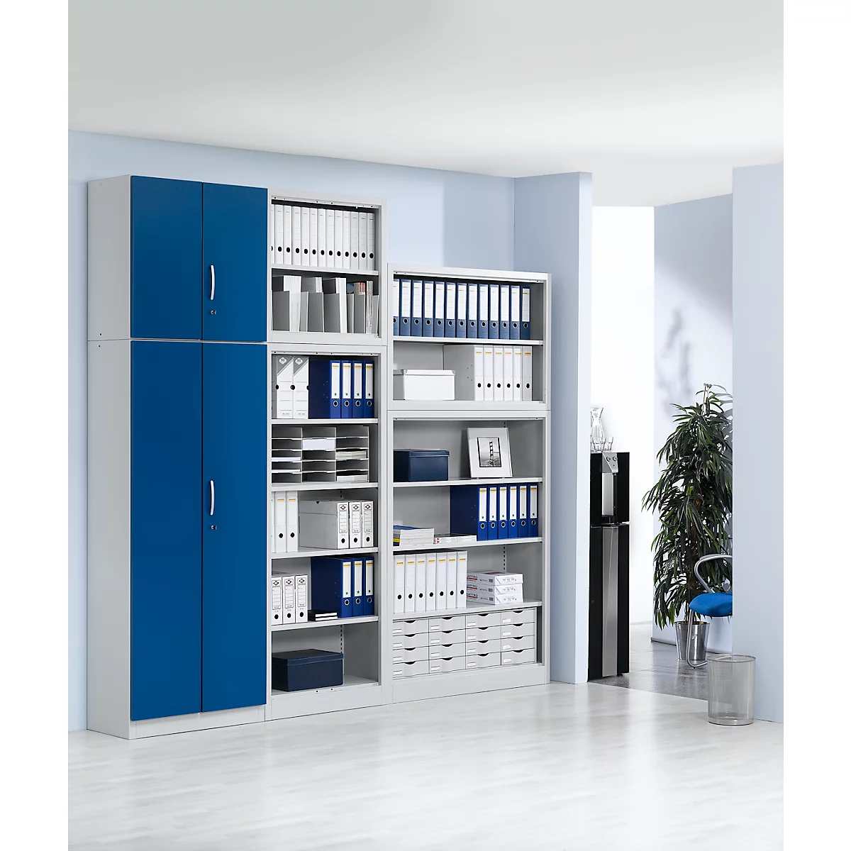 Office shelves in light gray and blue, filled with folders and documents. A clean, bright office space.