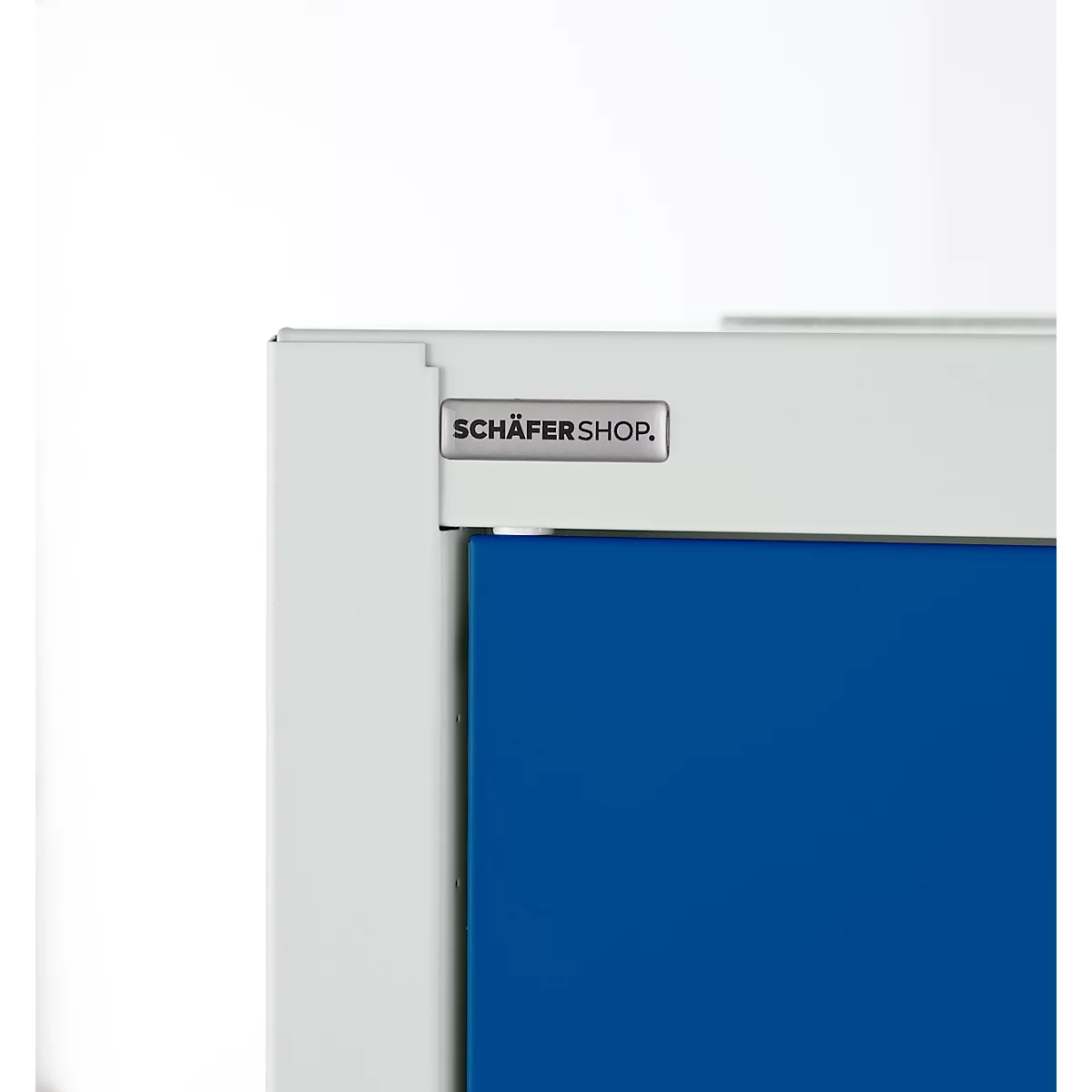 Gros plan d'une armoire avec le logo "SCHÄFERSHOP.". L'armoire a une porte bleue et un cadre blanc.