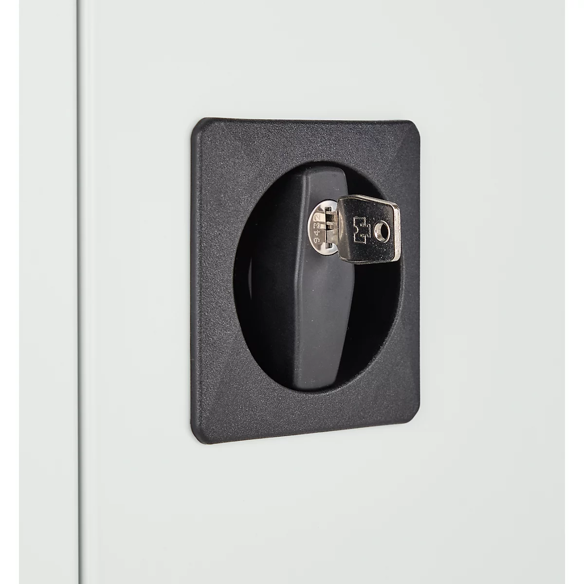 Gros plan d'une serrure noire avec une clé dans une armoire blanche.