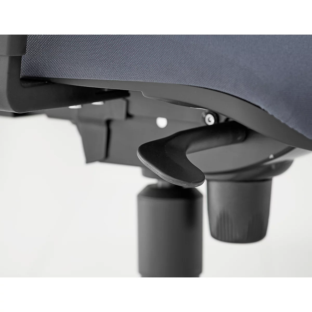 Gros plan du levier d'une chaise de bureau, noir, en métal et plastique. La chaise a une housse en tissu gris.