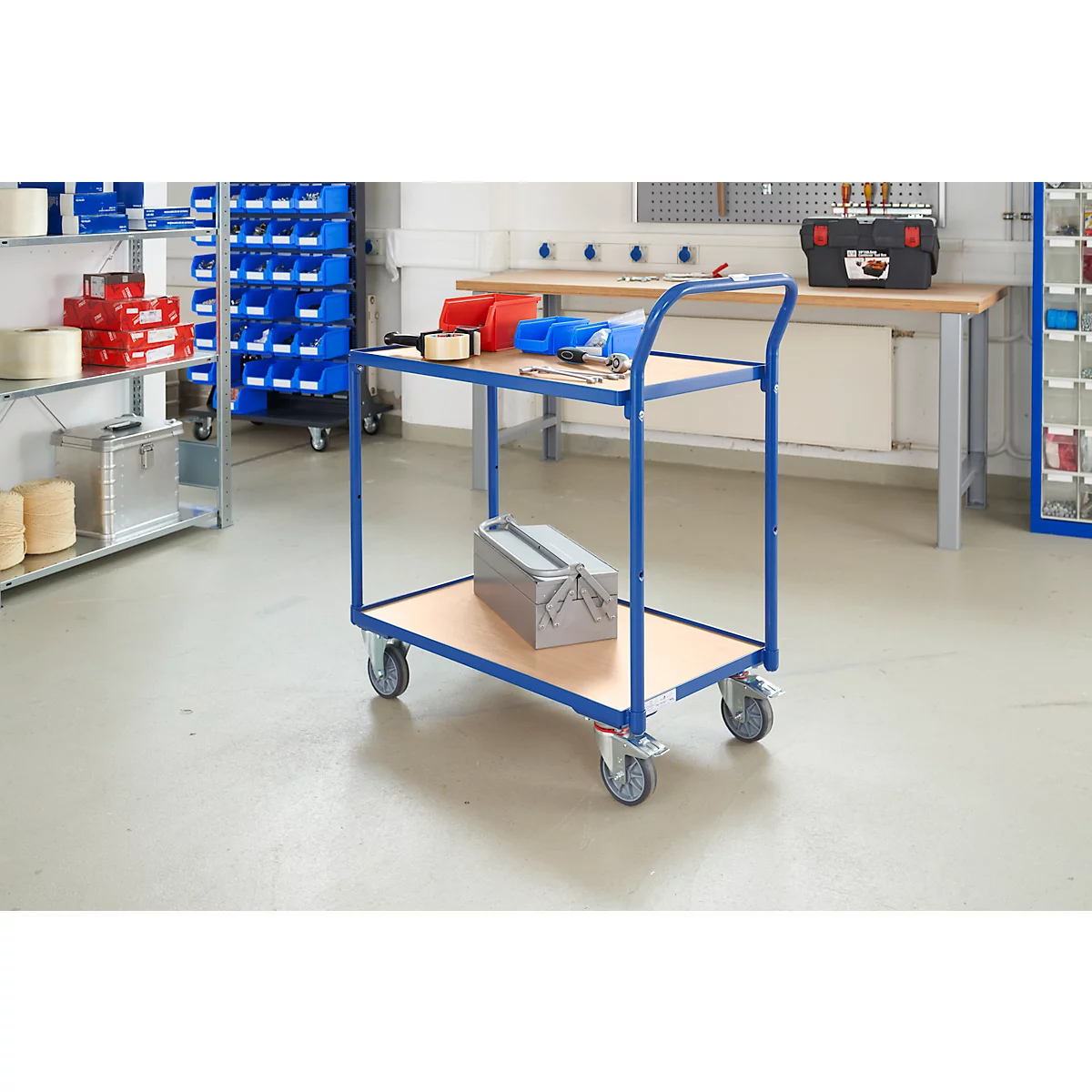 Chariot d'atelier bleu et argent avec outils et boîte à outils. Étagères et établi en arrière-plan.