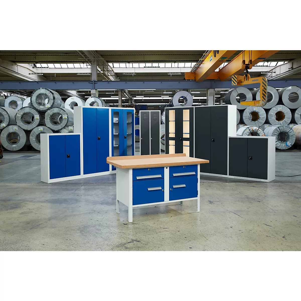Un établi et diverses armoires métalliques bleu et anthracite se trouvent dans une usine.