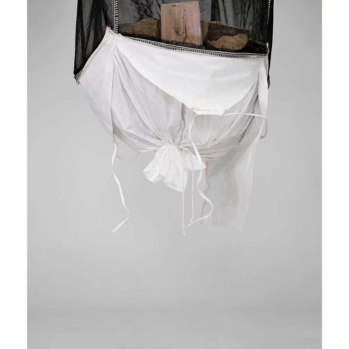 Vue d'en haut, une structure en filet noir soutenant un sac en tissu blanc contenant des morceaux de bois. Le sac est noué avec des ficelles.