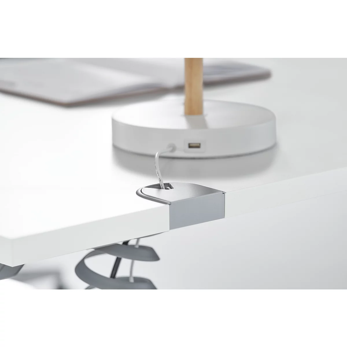 Gros plan: Une pince argentée fixant un connecteur USB à un dessus de table blanc.