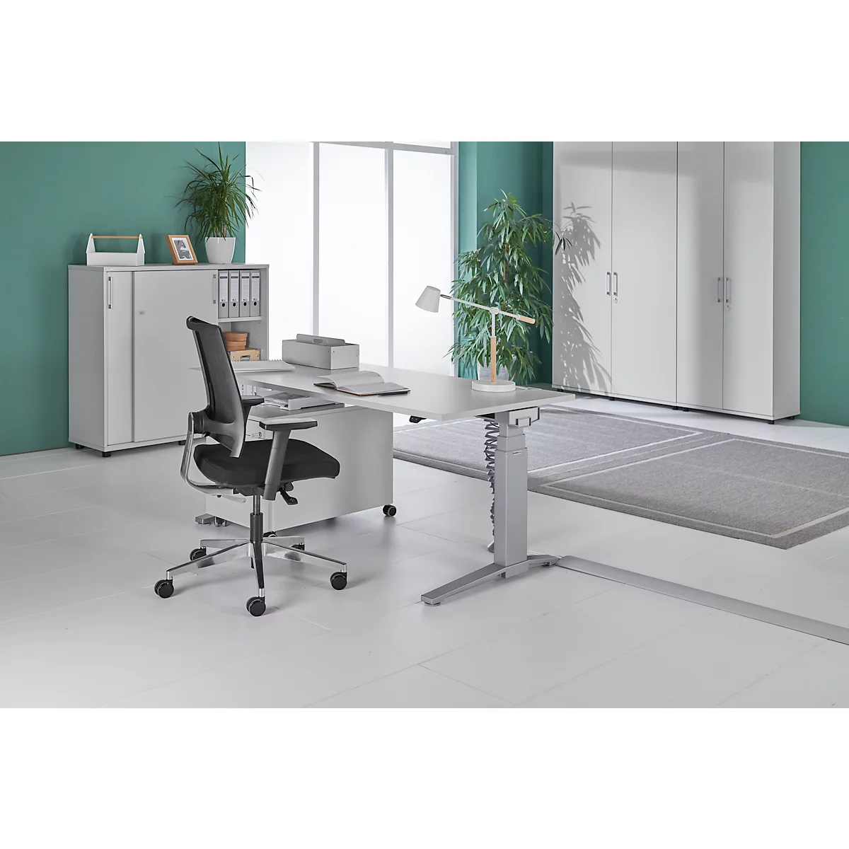 Lichte kantoorruimte met bureau, stoel en kasten. Op het bureau staan een printer en een lamp.
