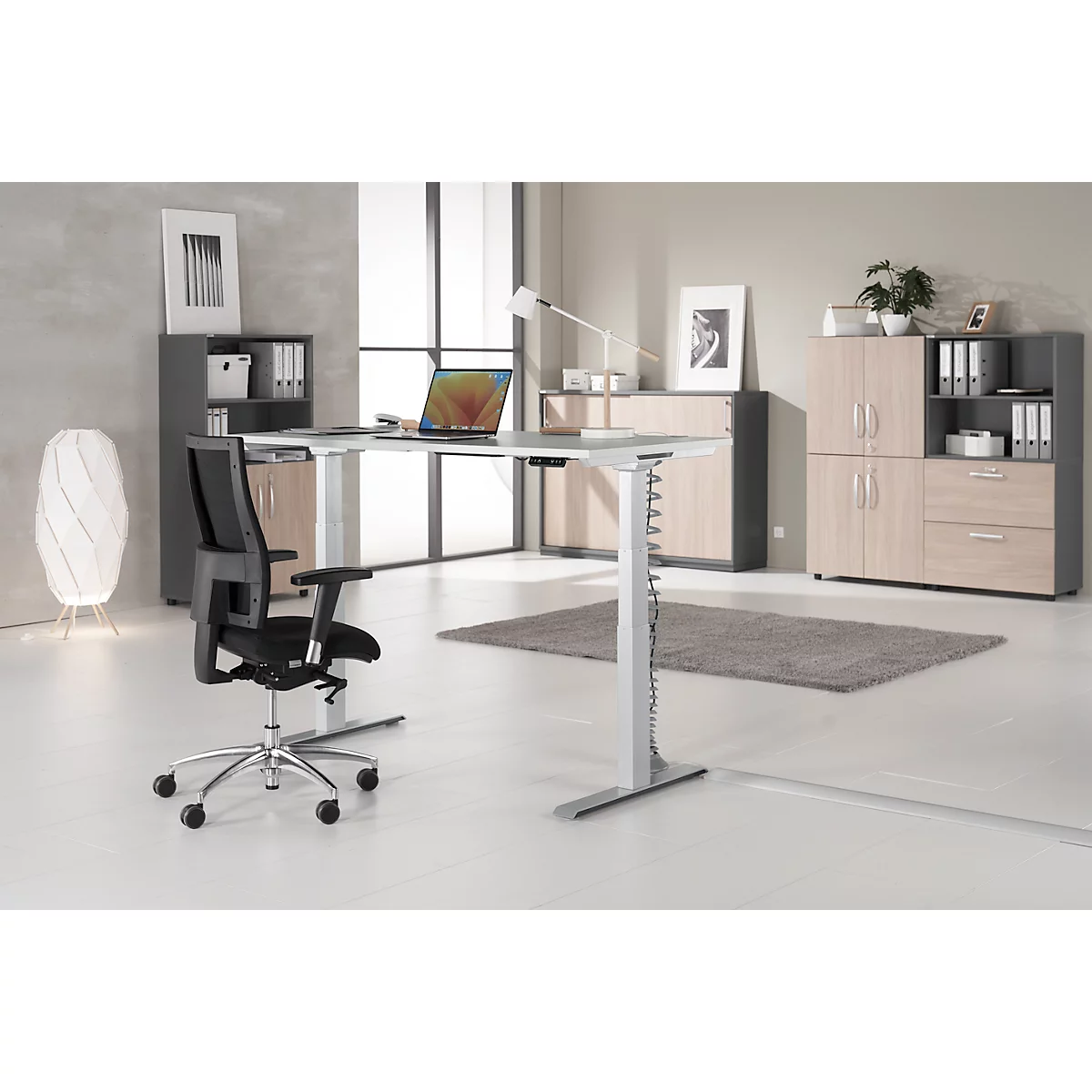 Office with height-adjustable desk, chair, cabinets, and laptop.