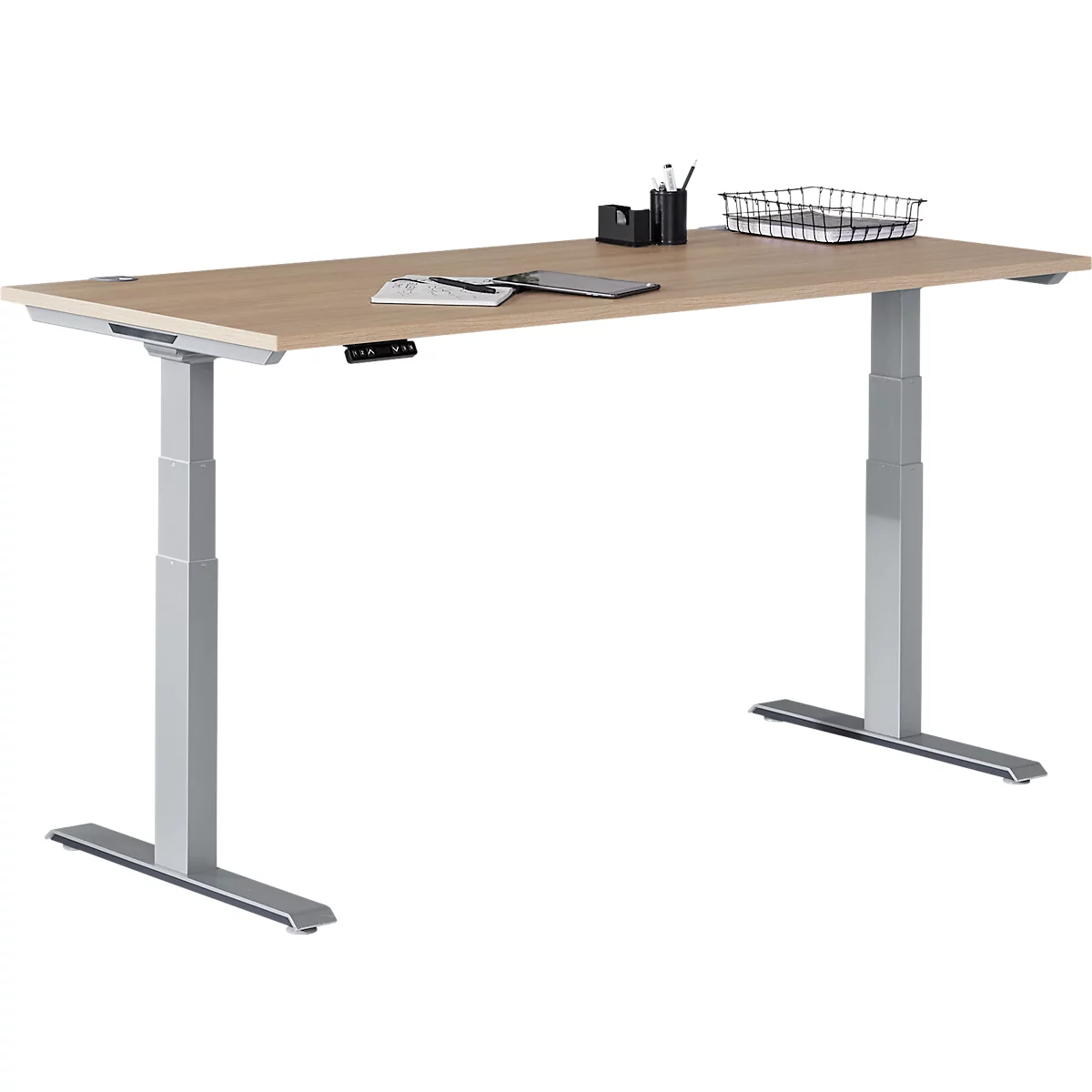 Height-adjustable desk with grey legs and a light wood top. Pens, paper, and a tray are on the top.