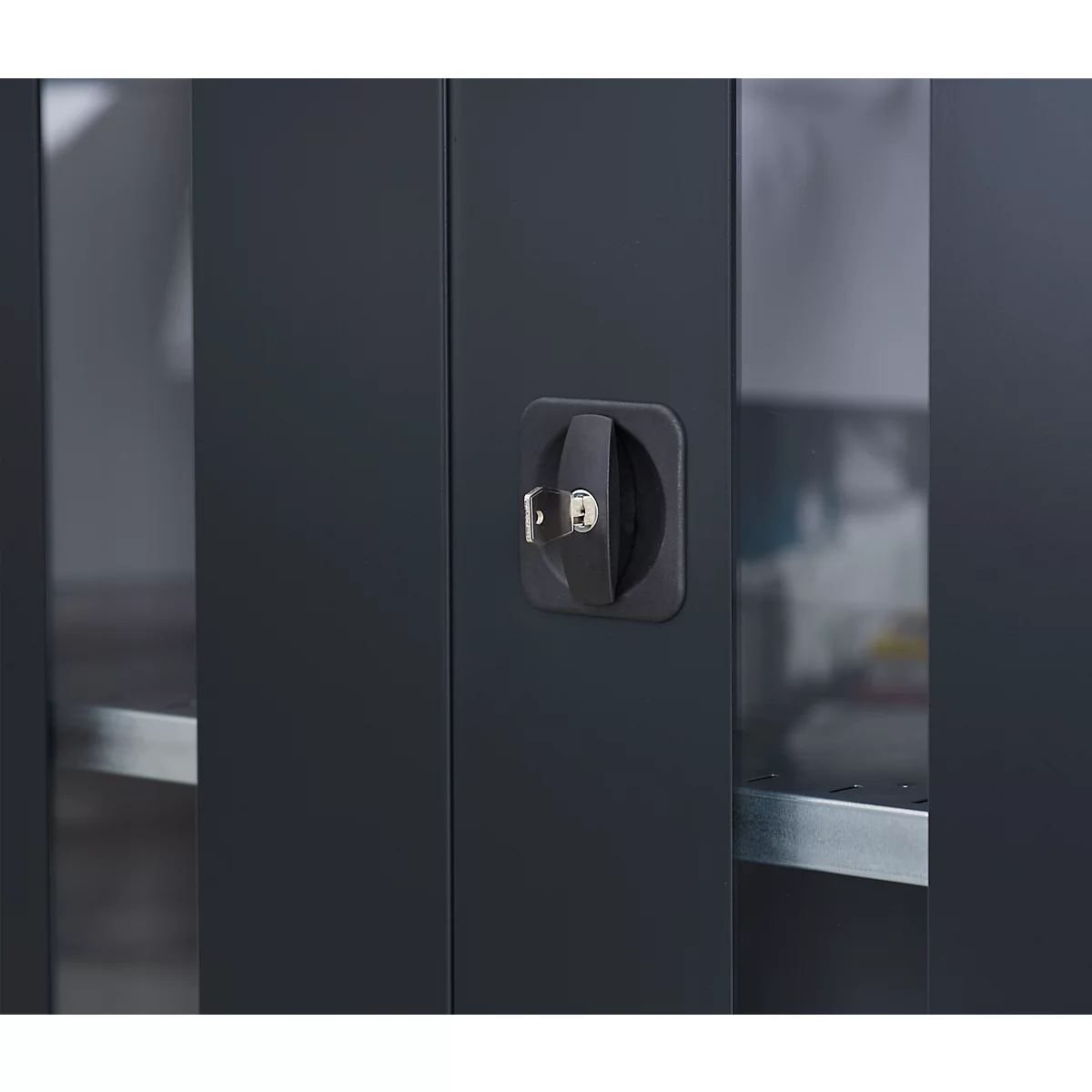 Close-up of a black cabinet door with a rotary handle and inserted key.
