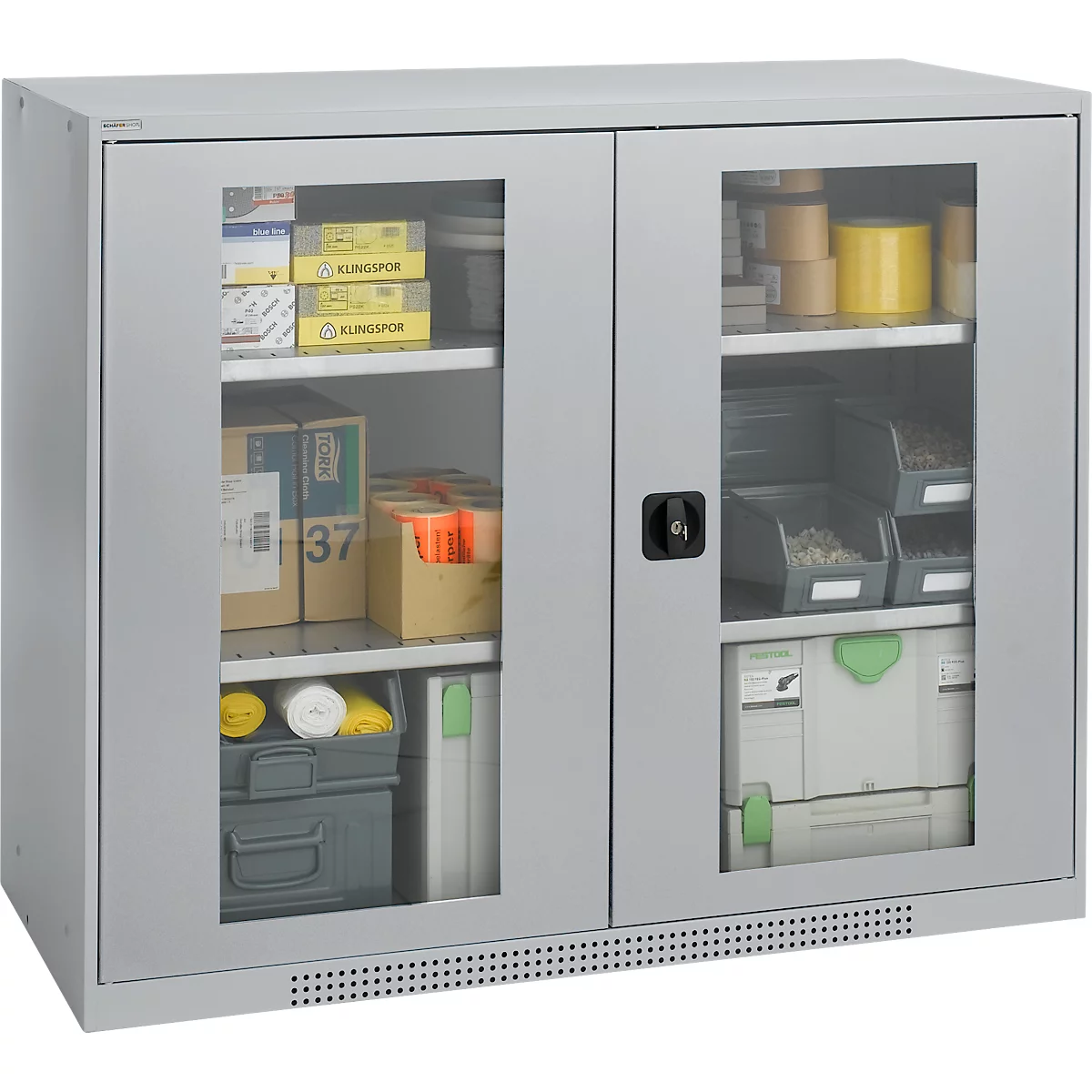 Grey cabinet with glass front, filled with tools, packaging and accessories. Black handle, ventilated bottom.