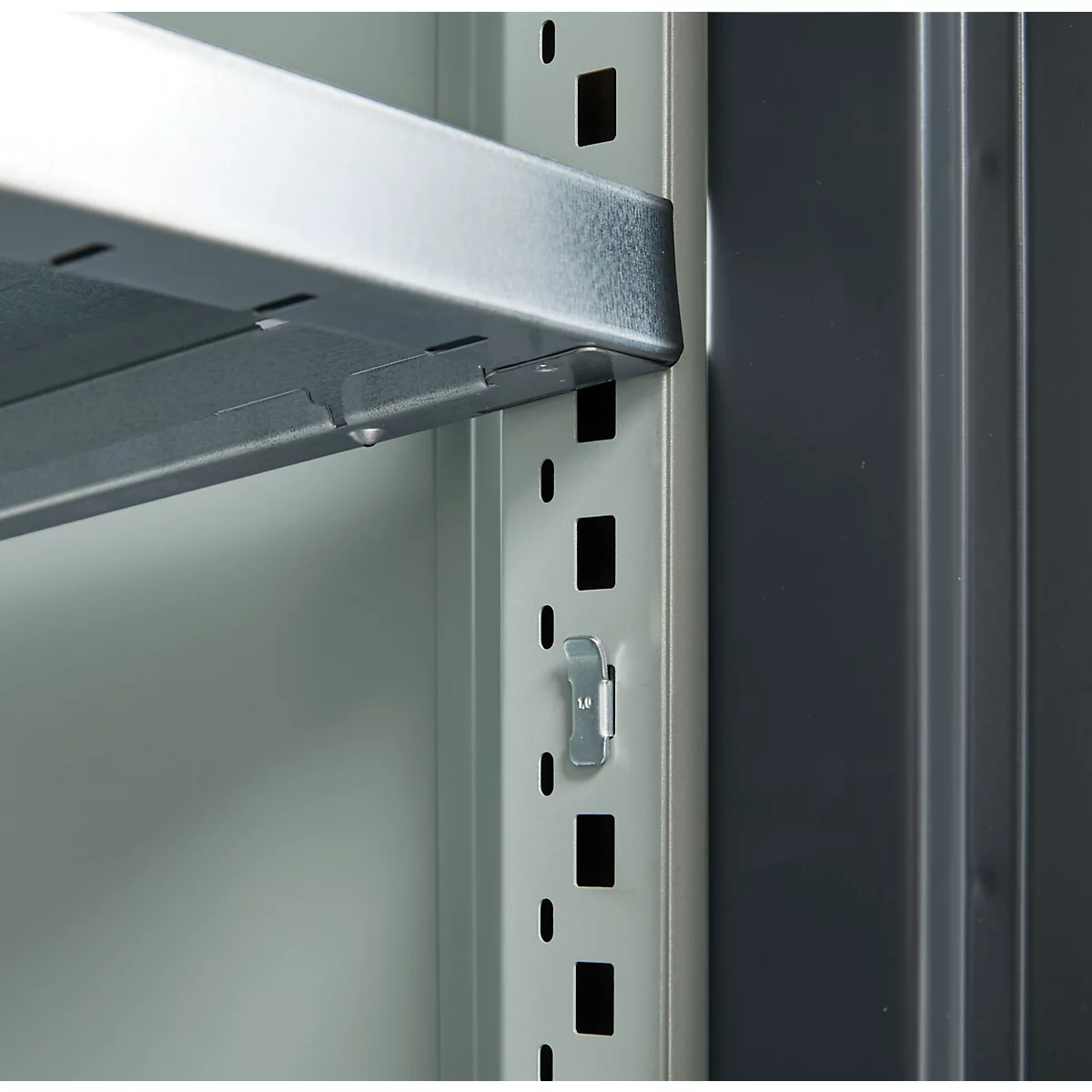 Close-up of a metallic shelving system. A silver shelf is held by a metal bracket, details.