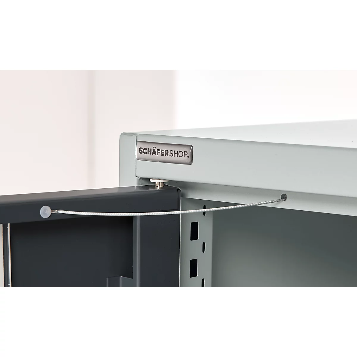 Grey metal cabinet corner with open door and 'SCHÄFERSHOP' lettering.