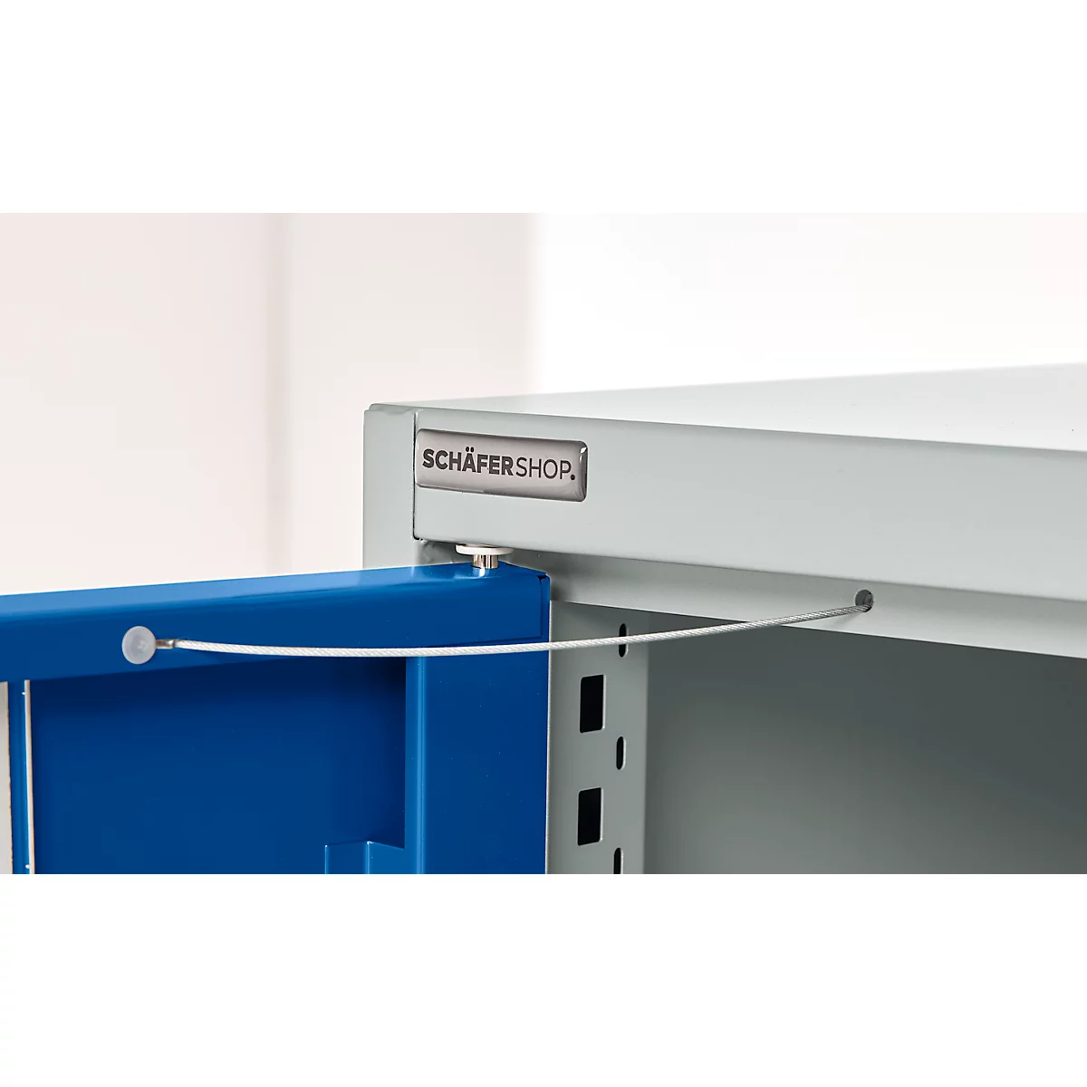 Close-up of a blue cabinet door with wire rope. The cabinet is grey, with the lettering SCHÄFERSHOP.
