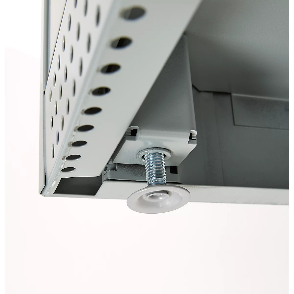 Close-up of a metal construction: corner connection with a hole pattern and adjustable foot. A thread protrudes from the foot.