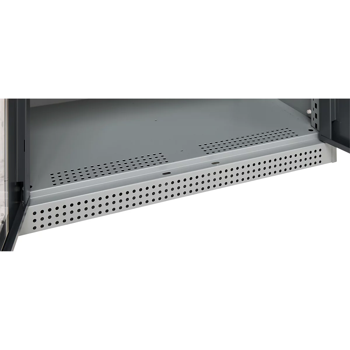 Close-up of a gray metal shelf with a perforated pattern. The shelf is integrated into a cabinet, the door is open.