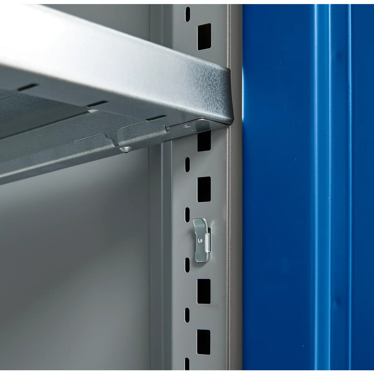 Close-up of a metal shelf. The gray shelves are attached to the blue side wall with brackets.