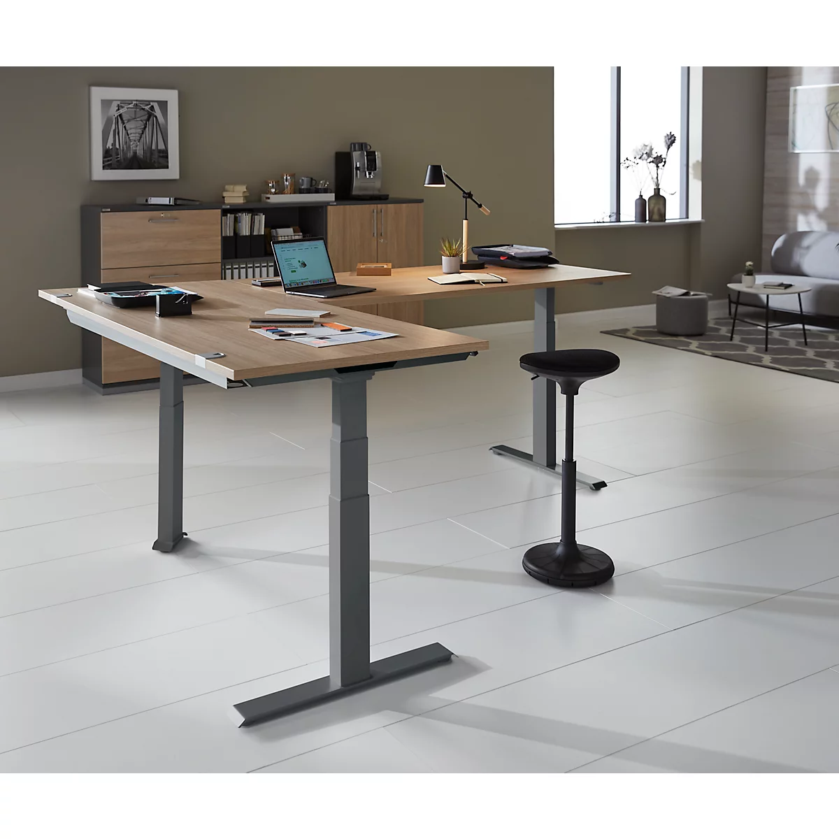 Een ergonomisch hoekbureau in houtlook. Daarop een laptop, pennen en notities. Achter het bureau een kast en een stahulp.