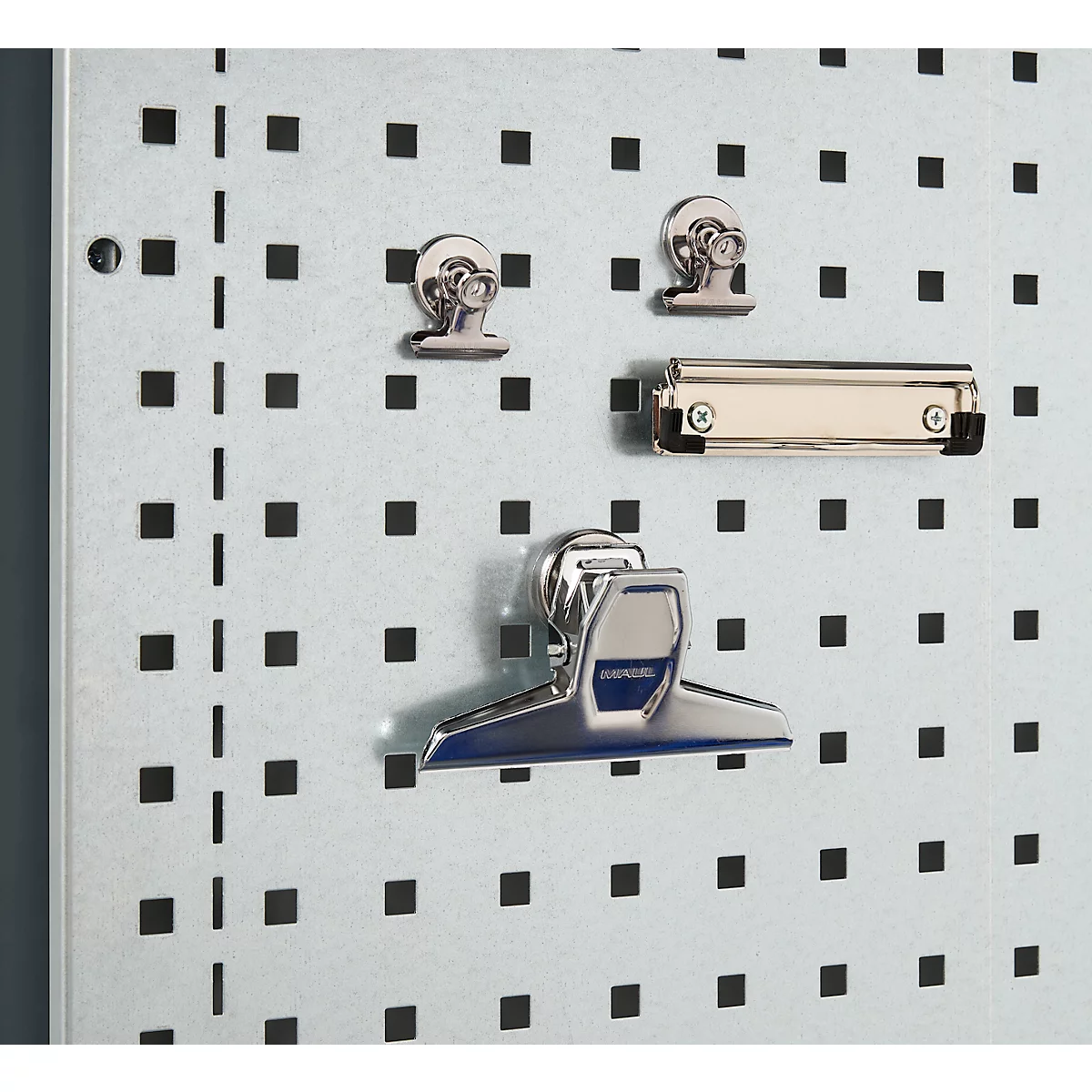 Nahaufnahme einer Lochwand mit Metallklammern und Klemmen, hellgrau mit schwarzen Quadraten.