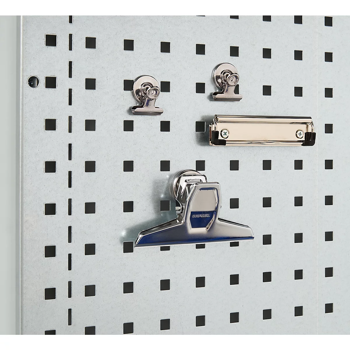Nahaufnahme einer Lochwand mit silbernen Clips und Klammern. Die Wand ist hellgrau mit gleichmäßig verteilten quadratischen Löchern.
