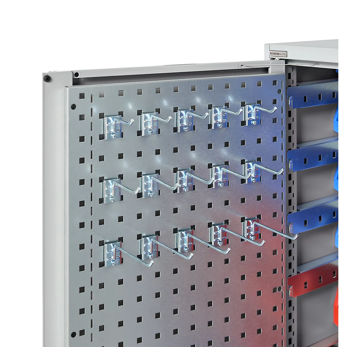 Metallschrank-Detailansicht: Lochblech mit Haken für Werkzeug und farbigen Leisten.