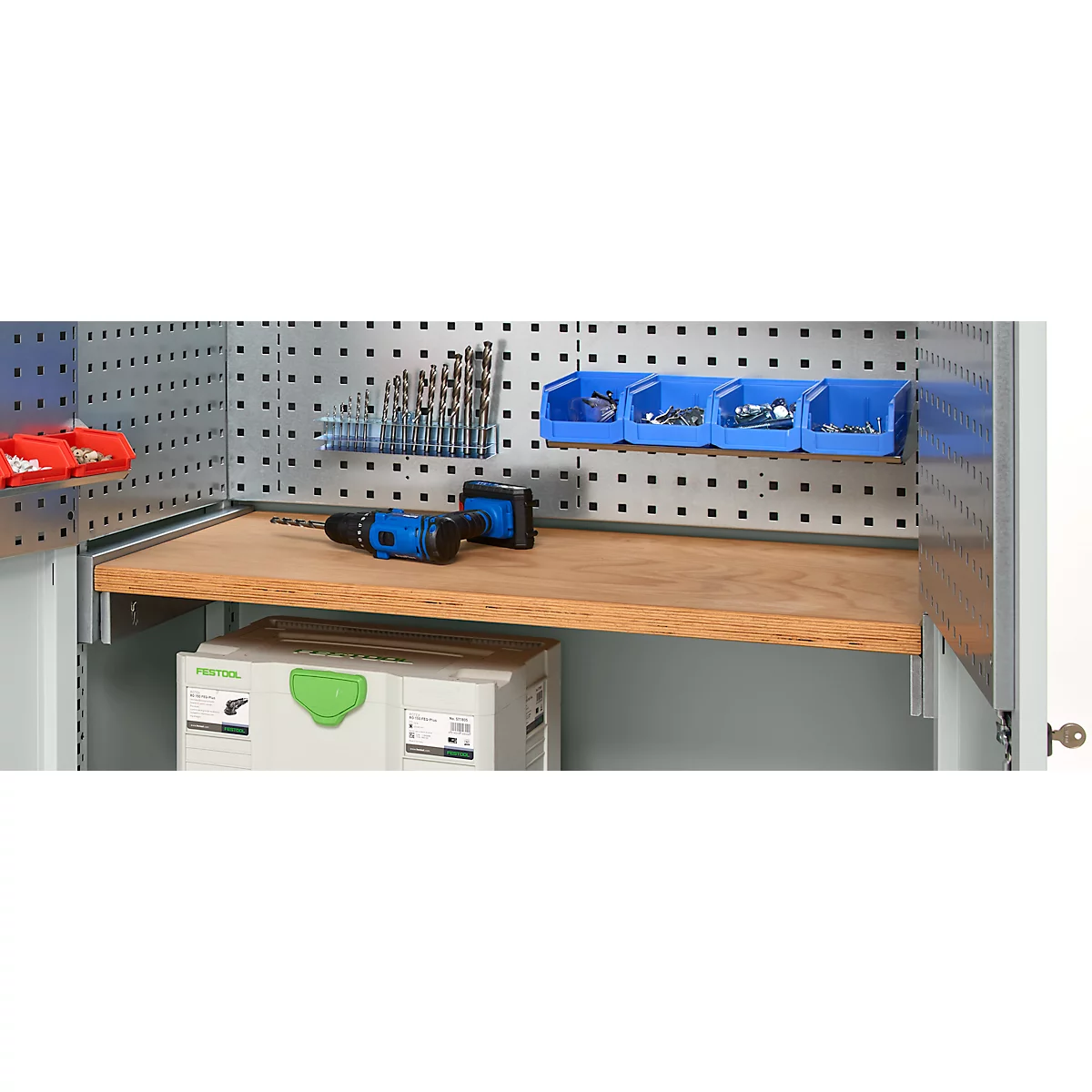 Tool cabinet with drill, drills, screws. Behind a wooden shelf stands a box.