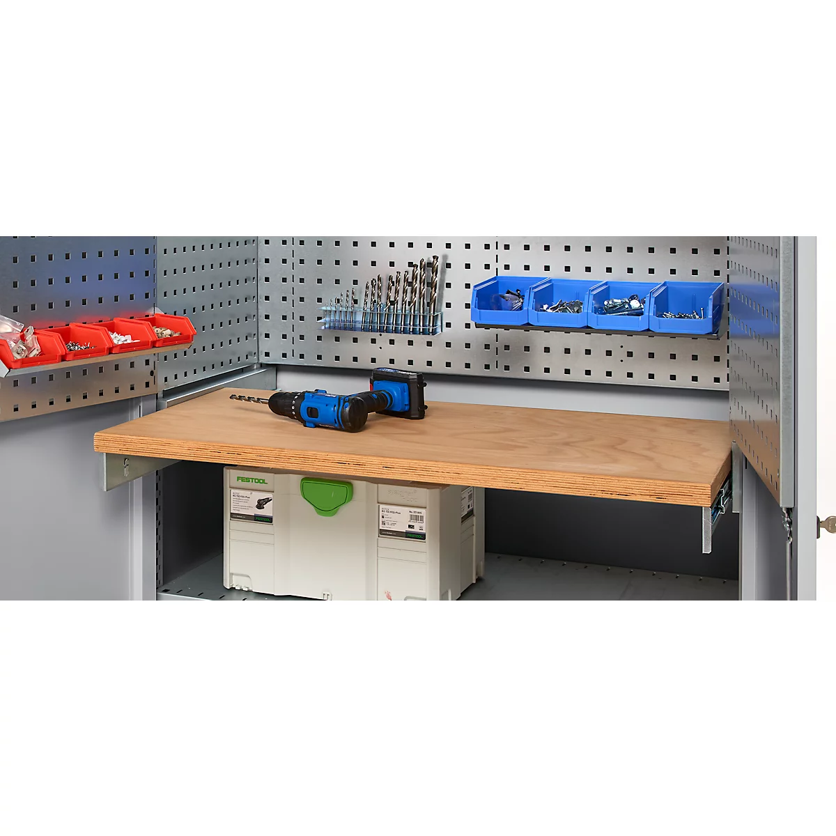 Workbench with wooden top, drill, drill bits, and blue tools. The back wall has holes and brackets for accessories.