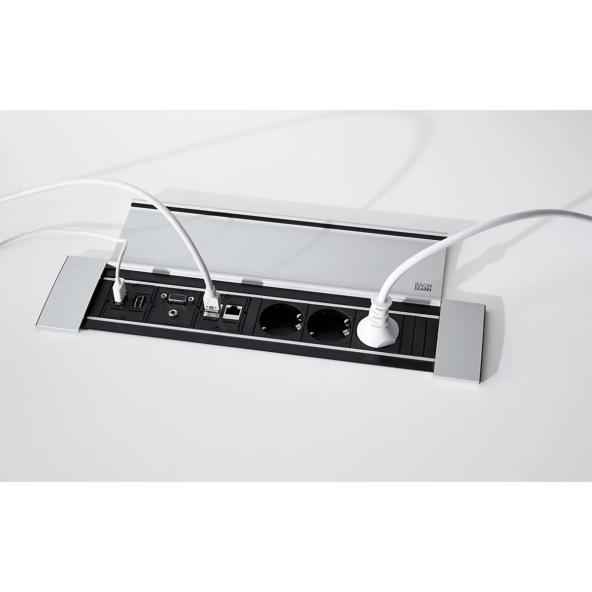 Una conexión de mesa gris con enchufes y conectores. Hay cables blancos enchufados. La tapa está ligeramente abierta.