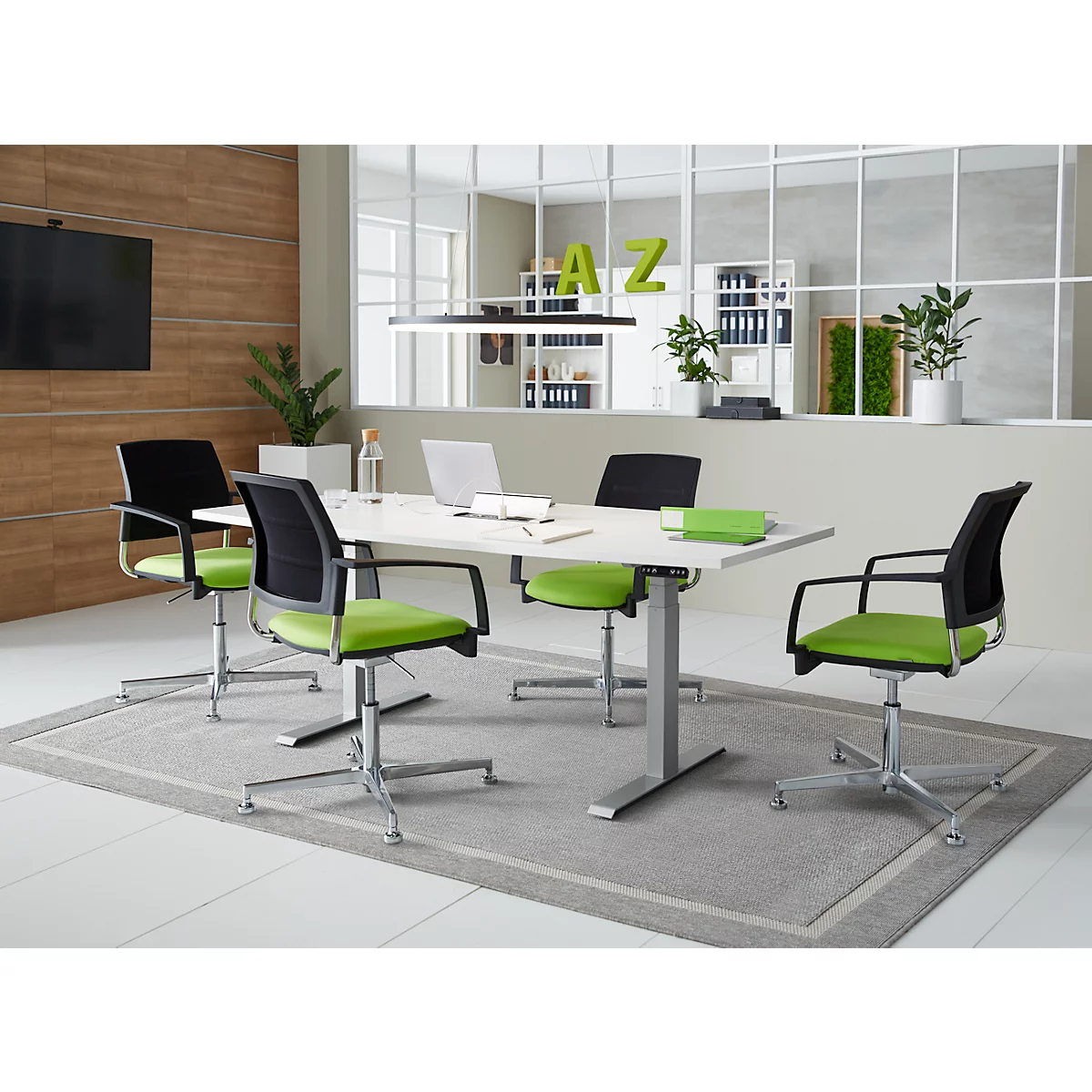Conference room with table, chairs and laptop. Green chairs, white table, carpet and glass wall. Letters AZ on the wall.