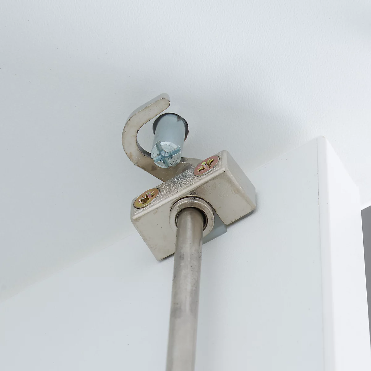 Close-up of a silver cabinet damper attached to a white cabinet door.