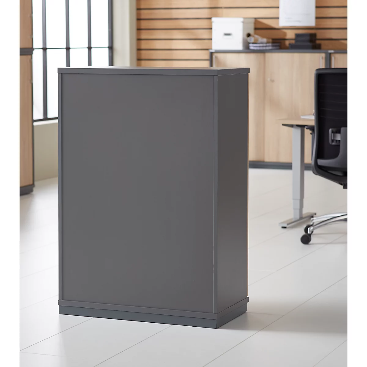 Grey cabinet in an office, light wood in the background. A window and a desk can also be seen.