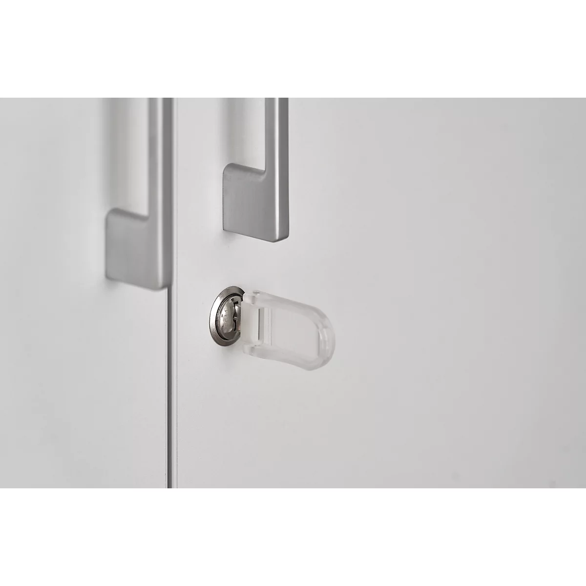 Close-up of a white cabinet door with handles and a lock. A clear key is in the keyhole.