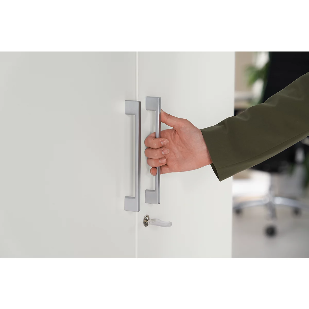 A hand opening a white door. The handle is silver.