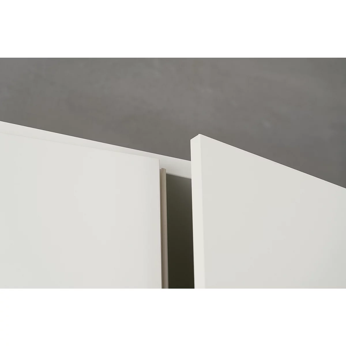 Close-up of white cabinet doors against a gray background. A gap is visible between the doors.