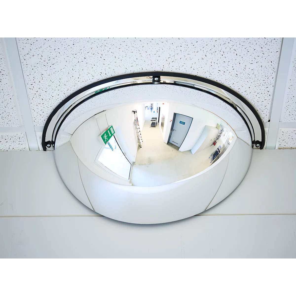 Un miroir de sécurité semi-circulaire est monté dans l'angle d'un faux plafond blanc.