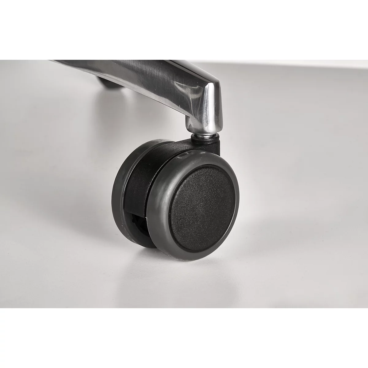 Close-up of a black office chair wheel. The wheel is made of plastic and is attached to a silver metal leg.