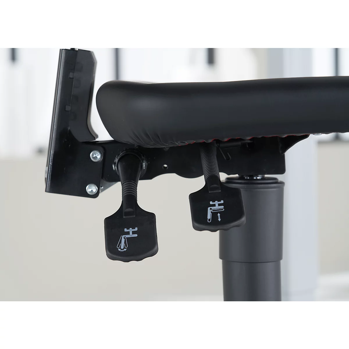 Nahaufnahme eines schwarzen Bürostuhls. Zwei Hebel mit Symbolen sind zu sehen.