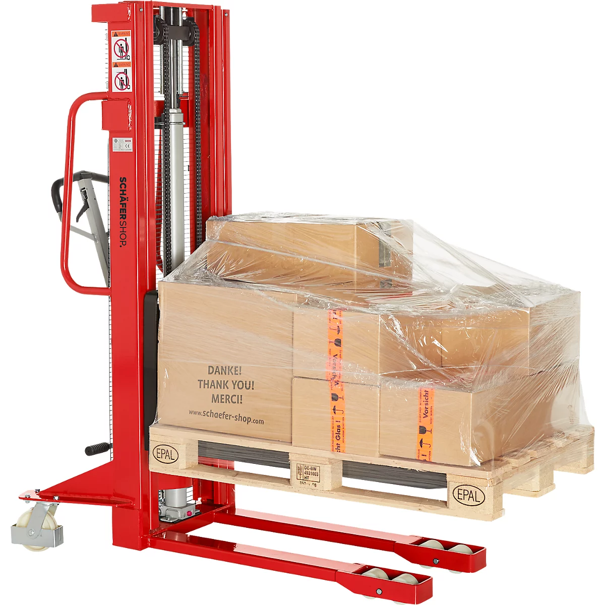 Red hand pallet truck with goods on a pallet. Pallets with boxes under foil, inscription 'Thank you!'.
