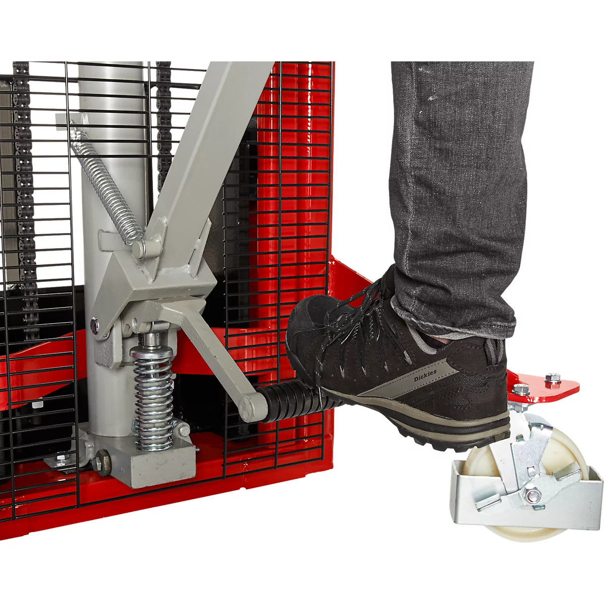 Detail shot: Foot pressing a pedal on a red pallet truck construction. The foot wears a black shoe.