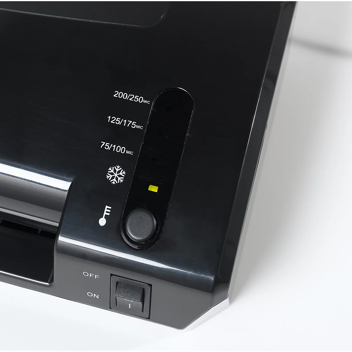 Close-up of a black laminator with control panel and temperature display. On-off switch, green indicator light, and setting options.