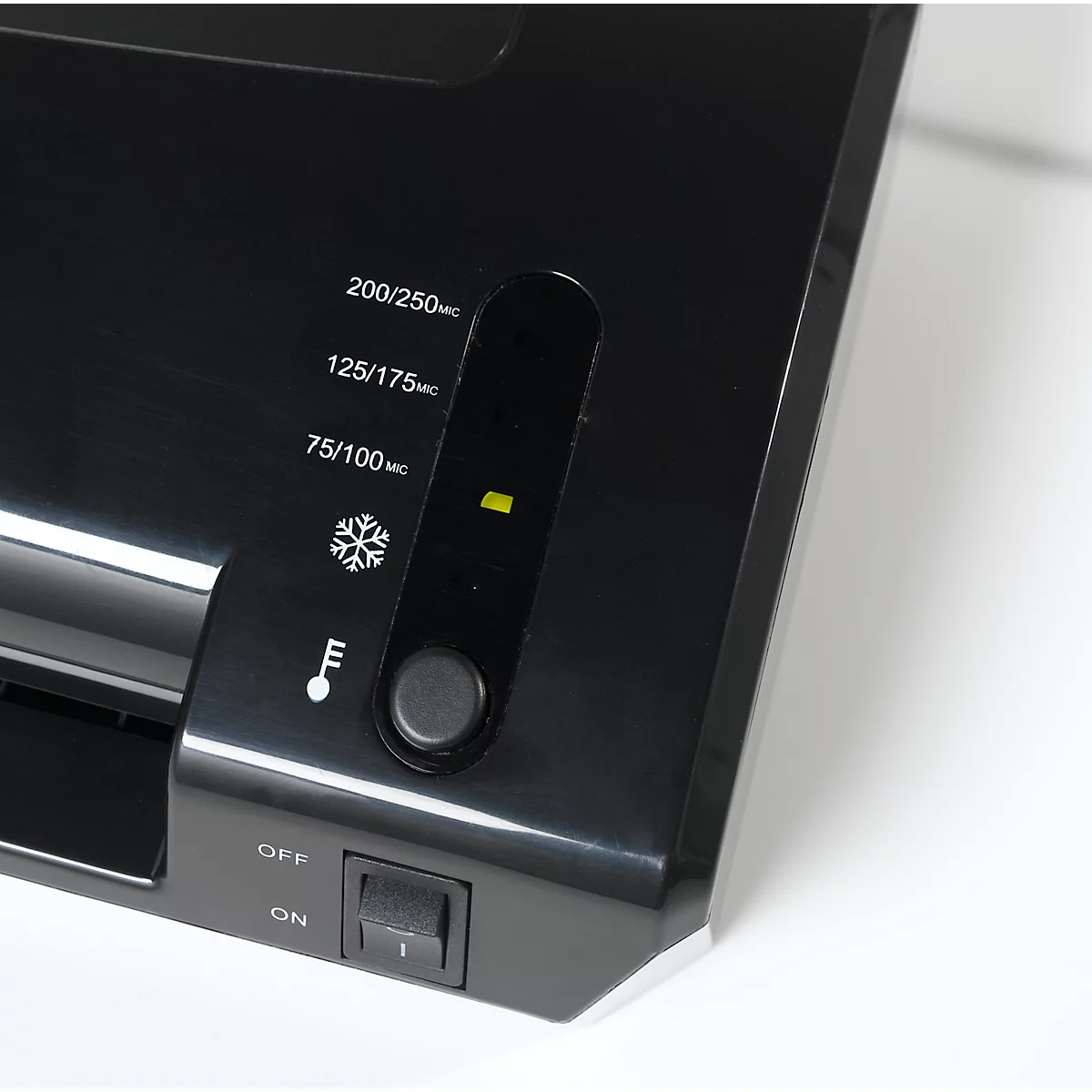 Close-up of a black laminator. Settings, temperature and indicator lights are visible on the surface.