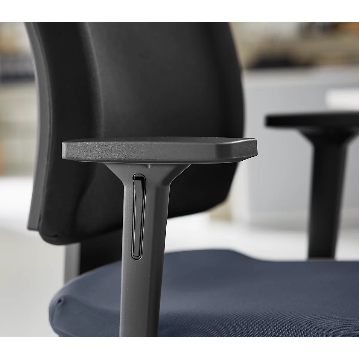Close-up of a black office chair, focusing on the armrest and backrest.