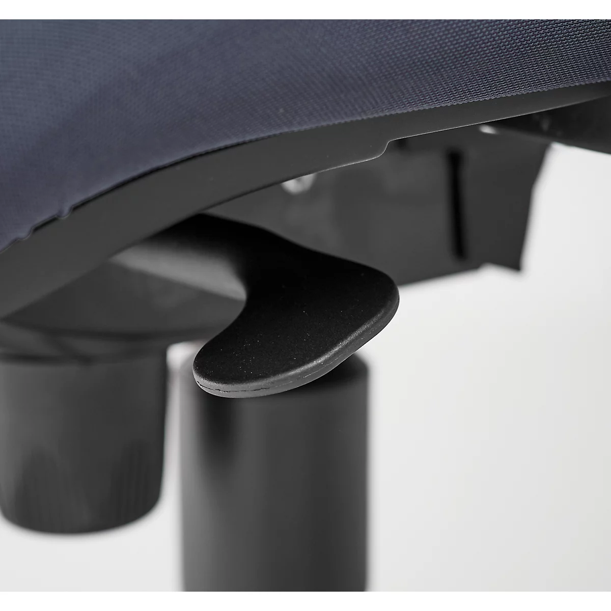 Close-up of a black lever device under a dark blue textile. In the background, a black column is visible.