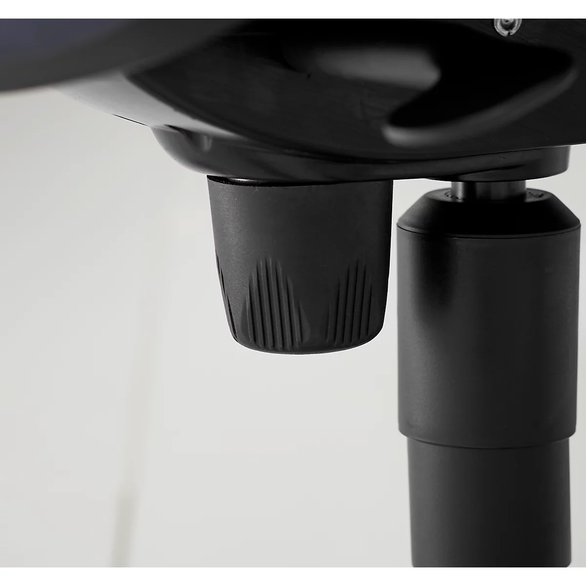 Close-up of a black object with a grooved surface. The background is white.