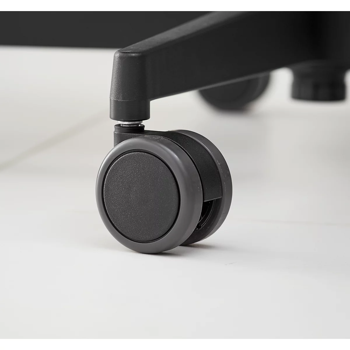 Close-up of a chair caster wheel. The chair is black, the wheel gray.