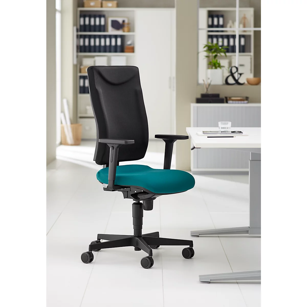 Office chair with black backrest and armrests. Teal seat. Castors, black frame.