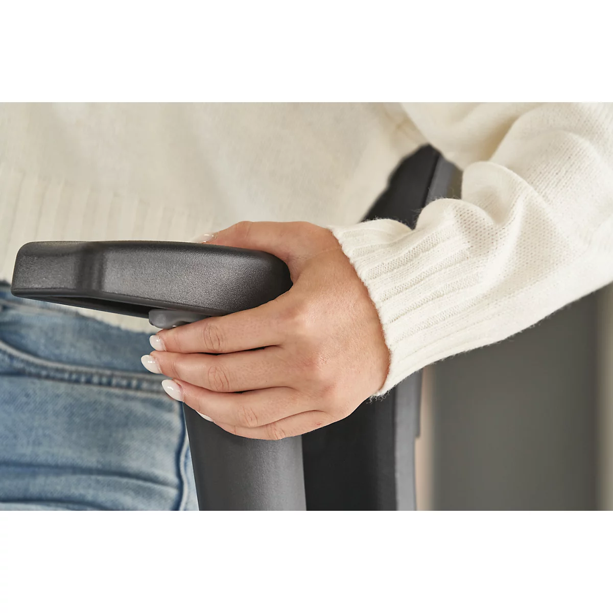 A person resting their hand on the armrest of an office chair. Pale skin, white clothing. Close-up shot.