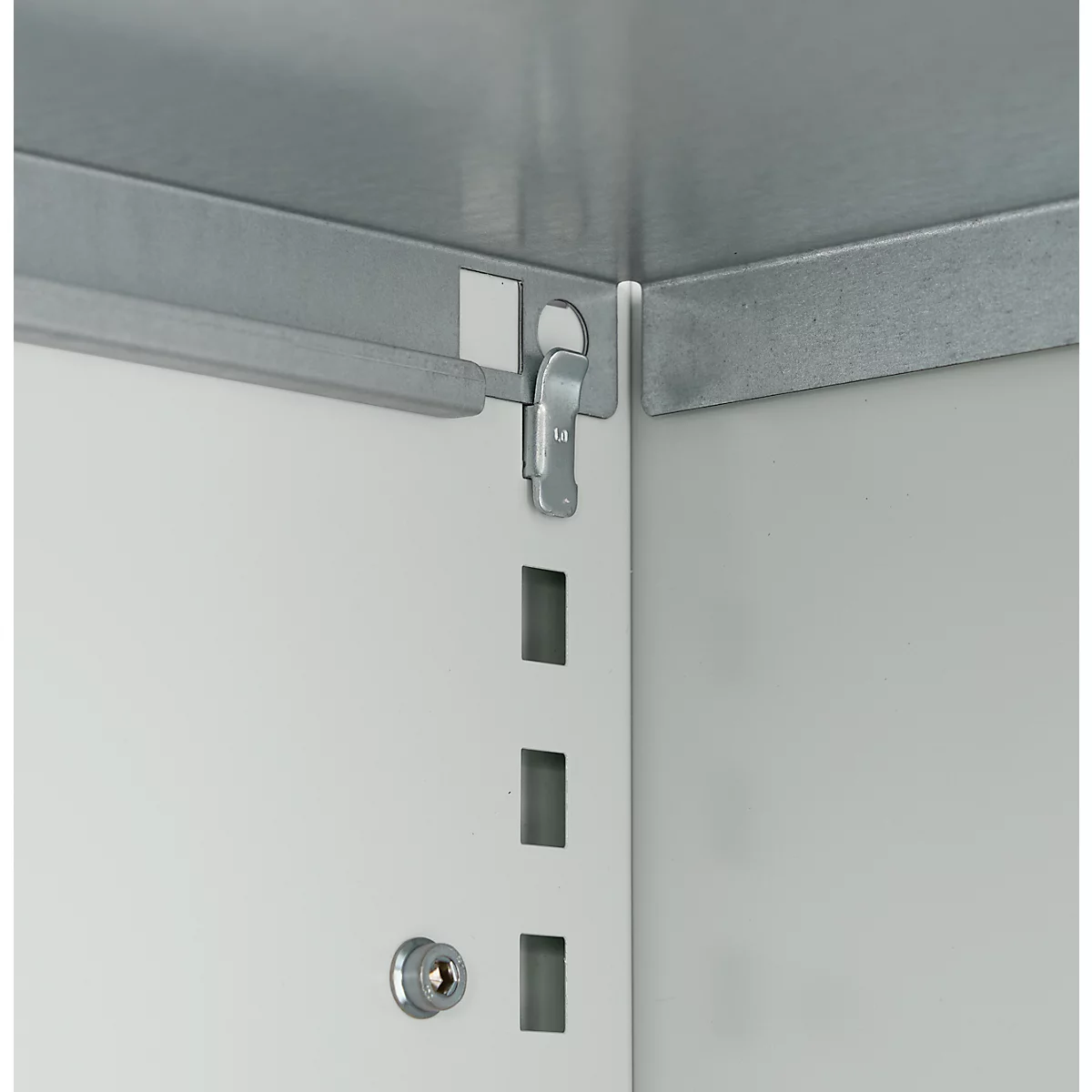 Close-up van een hoek van een kast met een zilveren metalen sluiting die aan een wit oppervlak is bevestigd.